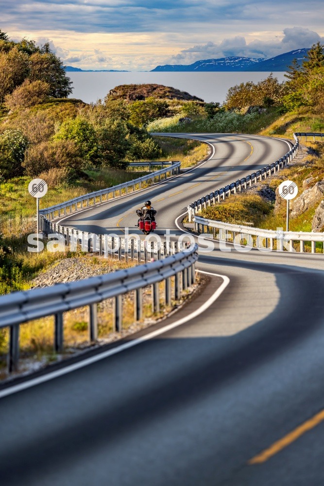 Couple rides a motorcycle on a winding Atlantic road in Norway. Atlantic Ocean Road or the Atlantic Road (Atlanterhavsveien) been awarded the title as &quot;Norwegian Construction of the Century&quot;
