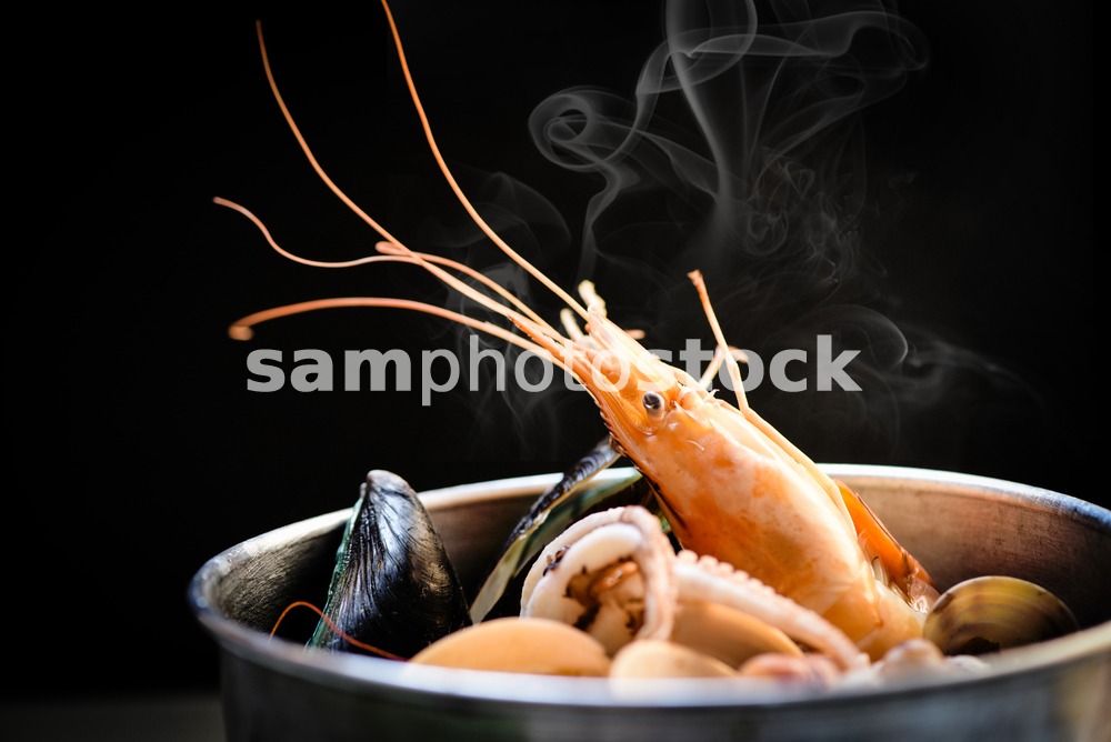 Shellfish seafood plate with shrimps prawns mussel squid ocean gourmet dinner seafood cooked boiled in hot pot with herbs and spices on dark background